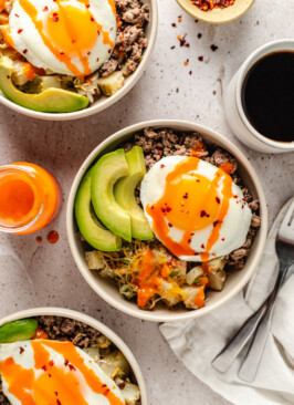 Venison Sausage Breakfast Bowl topped with avocado, hot sauce and red pepper flakes