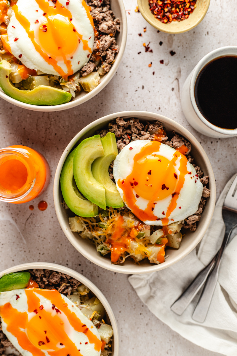 Venison Sausage Breakfast Bowl topped with avocado, hot sauce and red pepper flakes