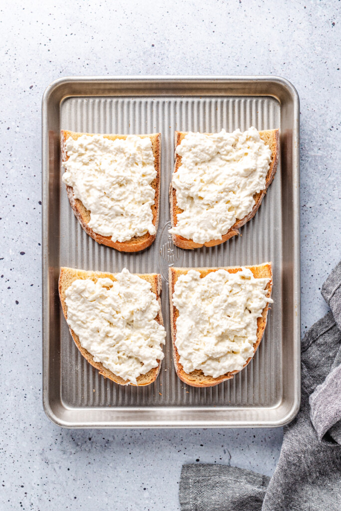 Burrata cheese spread on four pieces of toasted sourdough