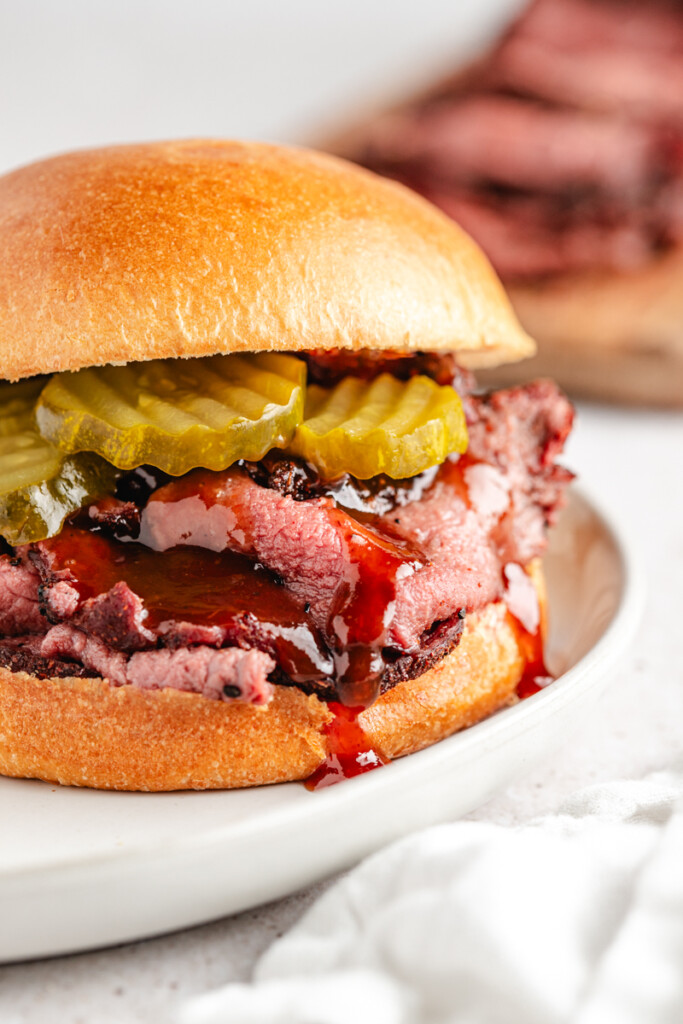A smoked venison roast sandwich with bbq sauce and pickles