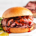 A smoked venison roast sandwich with bbq sauce dripping out