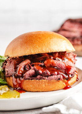 A smoked venison roast sandwich with bbq sauce dripping out
