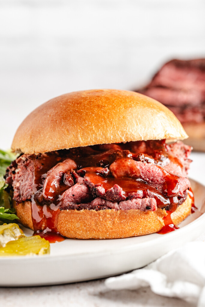 A smoked venison roast sandwich with bbq sauce dripping out