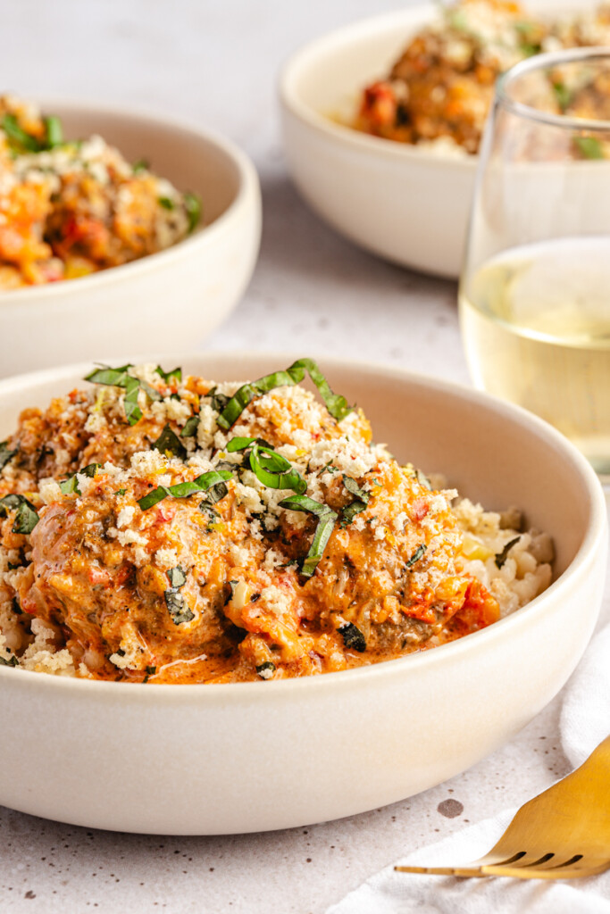 Marry Me Venison Meatballs served over risotto in a white bowl and garnished with lemon-basil breadcrumbs and fresh basil