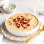 Chicken corn chowder in a white bowl garnished with bacon and green onions