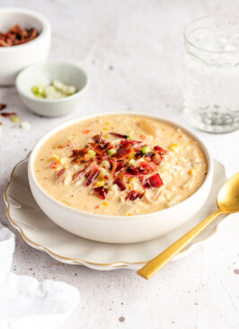 Chicken corn chowder in a white bowl garnished with bacon and green onions