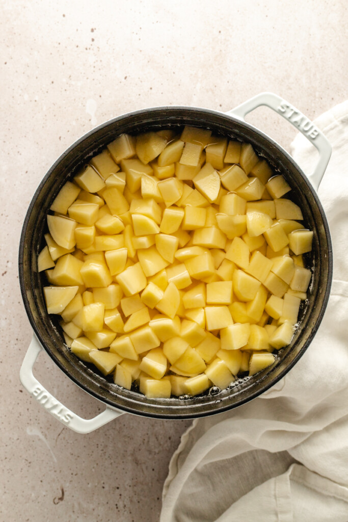 Diced gold potatoes in a white pot with water
