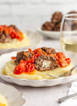 Pepper jack cheese inside of a cut in half meatball served with mashed potatoes and bacon jam