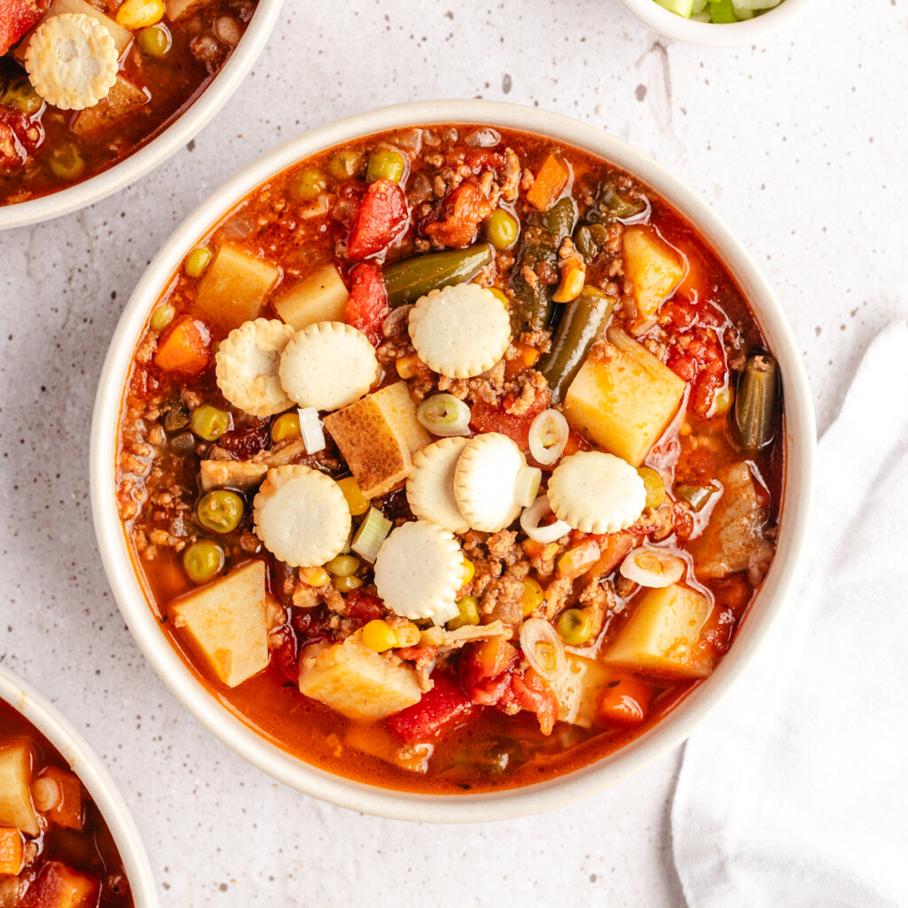 Hamburger soup in a white bowl topped with oyster crackers