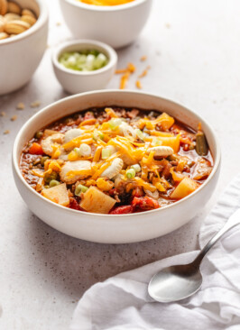 A bowl of hamburger soup in a white bowl served with toppings