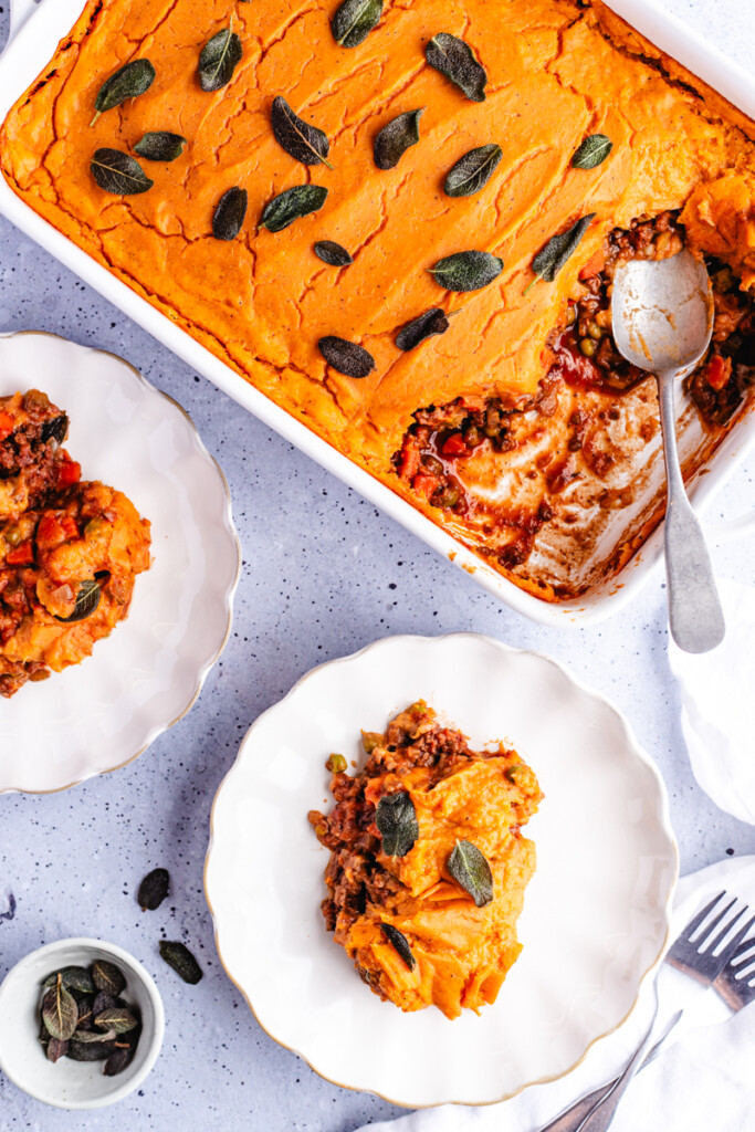 Two white plates being served with Sweet Potato Shepherd's Pie