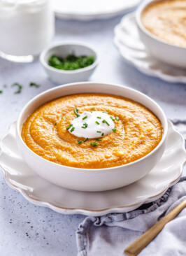 Butternut squash soup in a white bowl topped with sour cream and chives