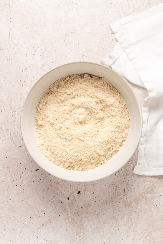 Flour with butter cut into it in a white mixing bowl