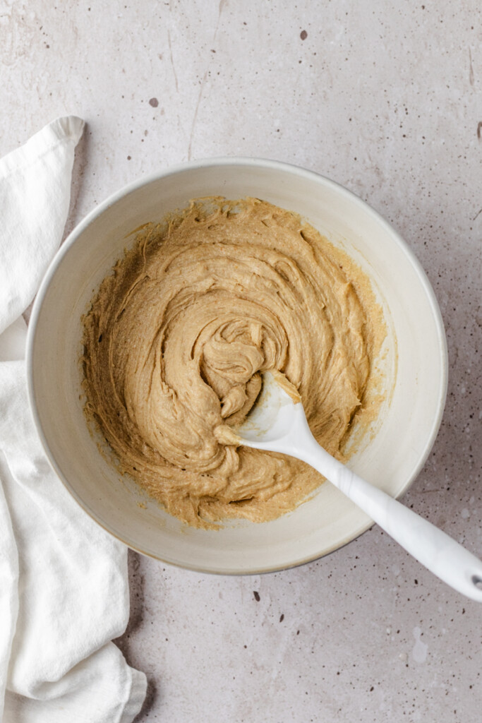Browned butter, sugars and eggs mixed together in white mixing bowl