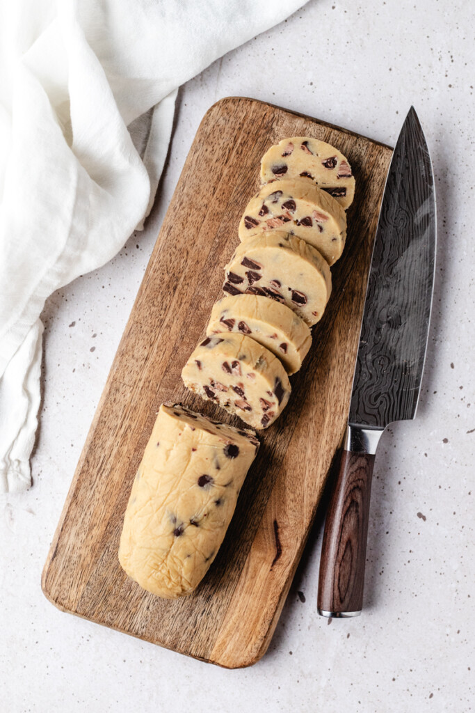 Frozen Brown Butter Slice & Bake Chocolate Chip Cookie dough being sliced on cutting board