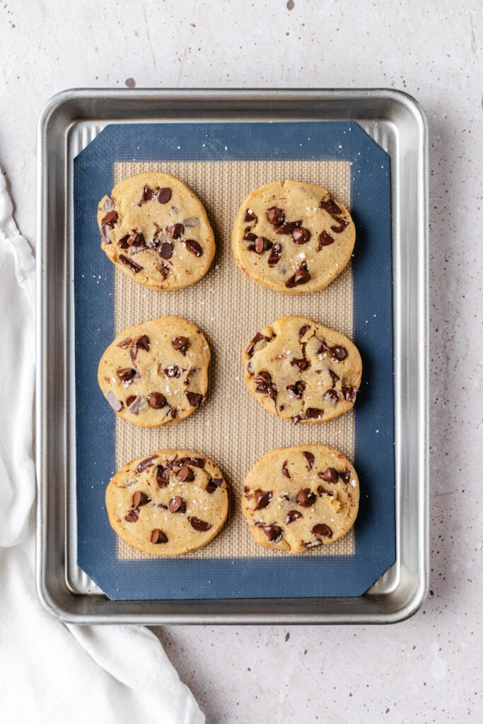 6 Brown Butter Slice & Bake Chocolate Chip Cookies baked on silpat lined cookie tray, topped with flakey sea salt