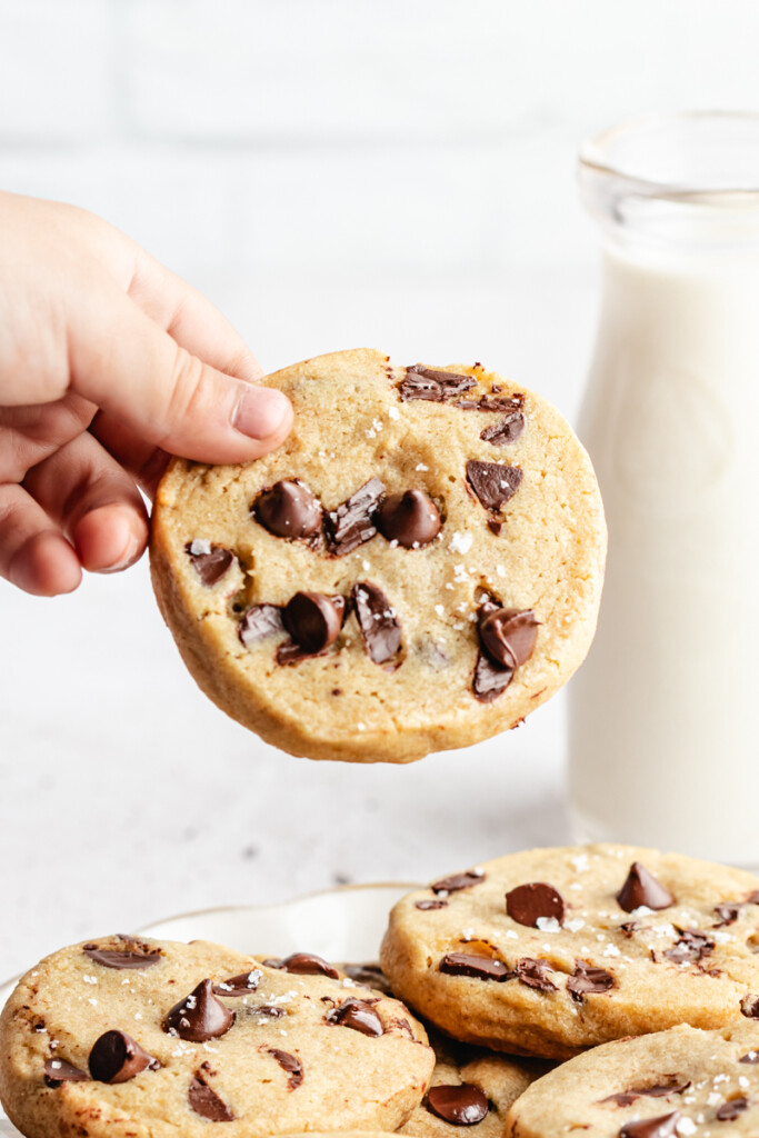 A childs hand holding a Brown Butter Slice & Bake Chocolate Chip Cookie