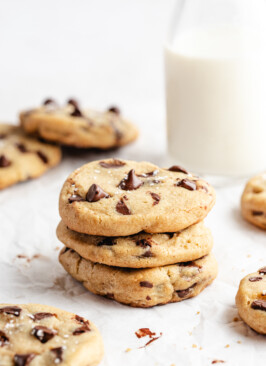Three Brown Butter Slice & Bake Chocolate Chip Cookies stacked on top of each other with milk behind them
