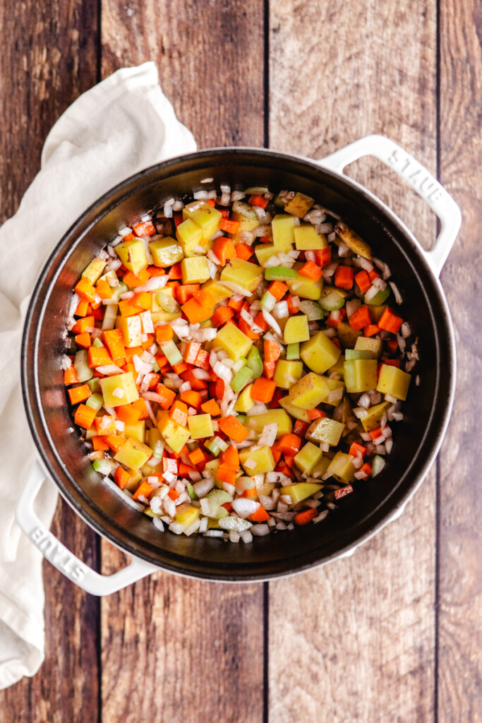 Potatoes, celery, onions and carrots sautéing in a soup pot