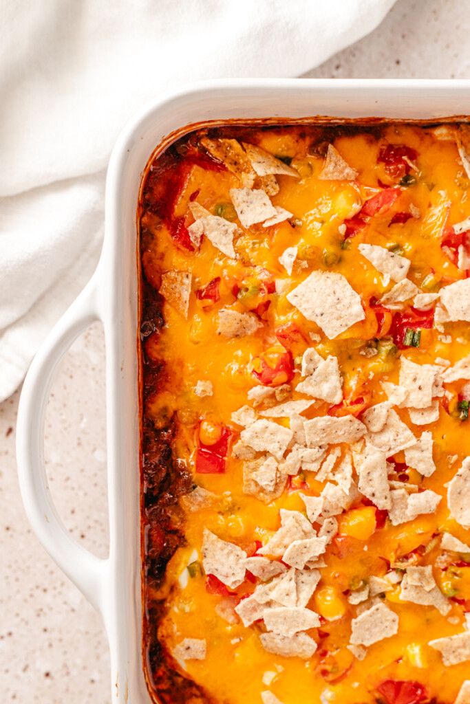 close up of high protein taco casserole topped with shredded cheddar cheese.