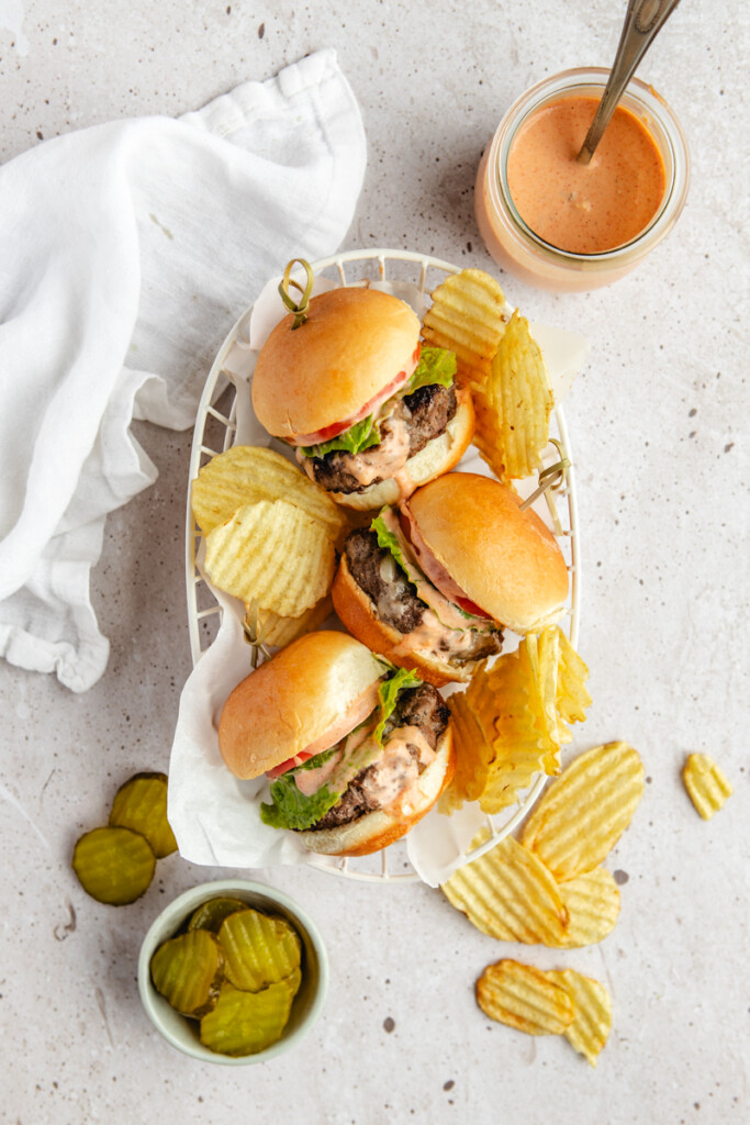 Three venison slider burgers in a basket with chips