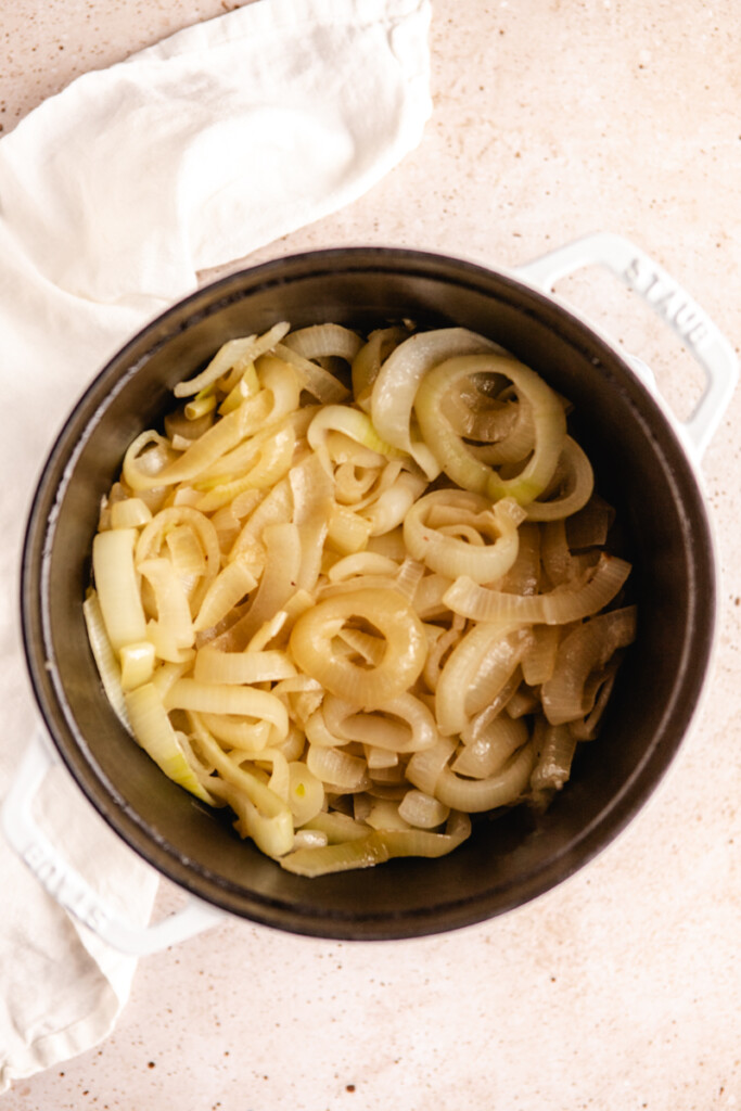 Sliced onions cooking down in a dutch oven for French onion soup