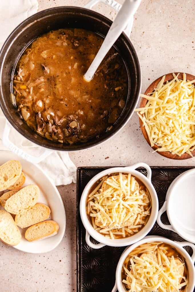 Prepping French Onion Soup with Braised Meat into bowls and topping with cheese