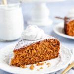A piece of Fresh Ginger Orange cake on a white plate topped with thyme ginger cream