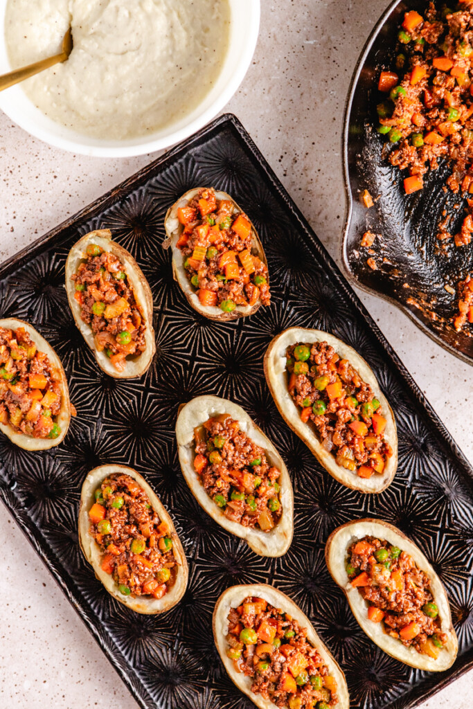 Baked potatoes stuffed with shepherds pie filling on a black tray