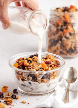 Milk pouring over the best granola in a glass bowl