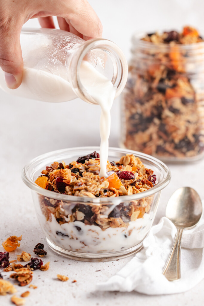 Milk pouring over the best granola in a glass bowl